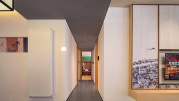 A hallway with a radiator, a framed picture, and a poster on the wall.