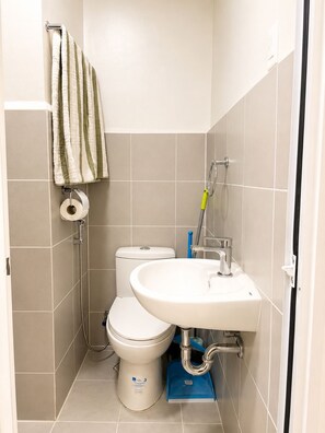 Et badeværelse med toilet, vask og bruser.