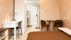 Une chambre moderne avec un lit, un bureau, deux chaises et une petite table.