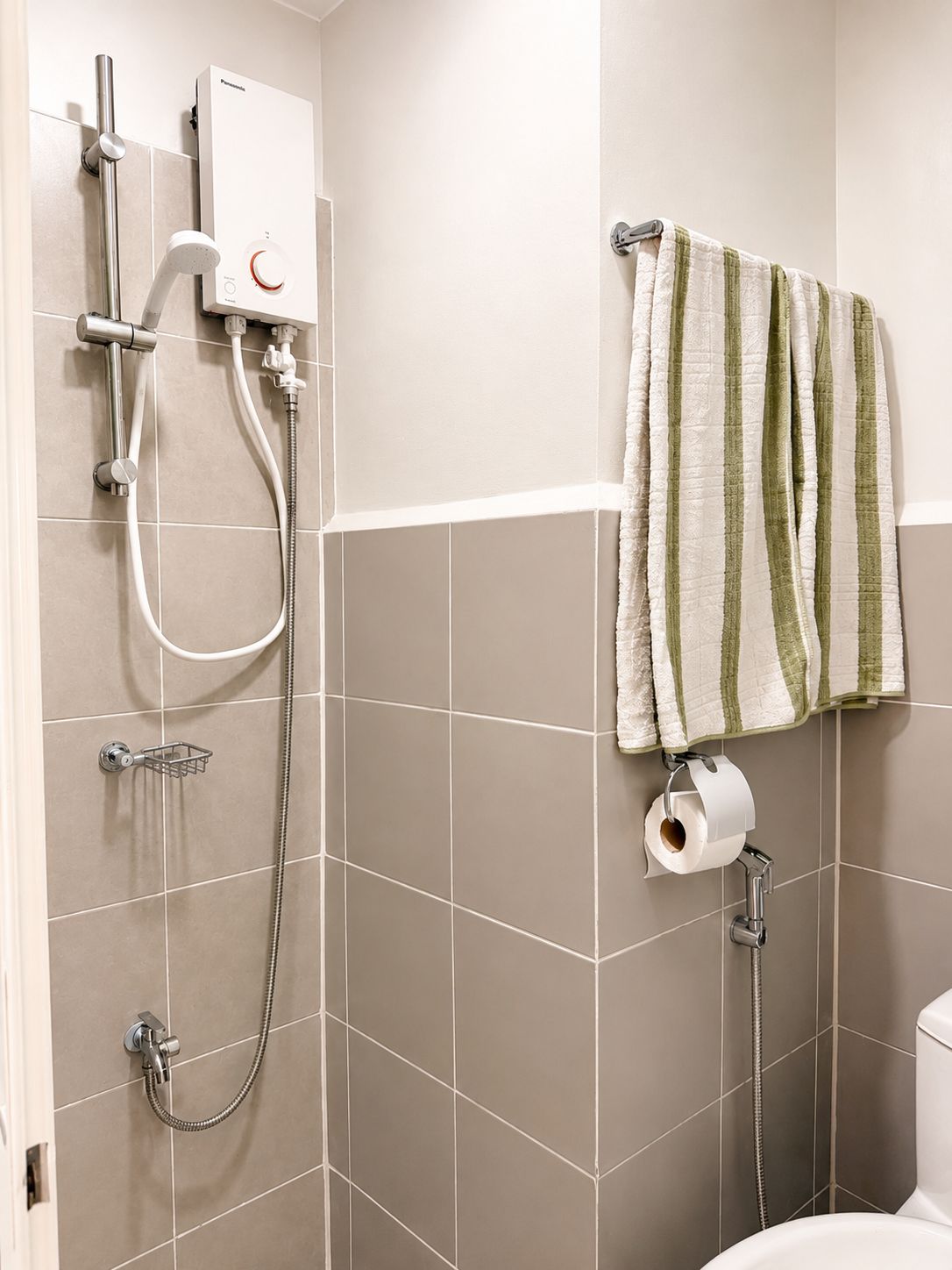 Une salle de bain avec douche, toilettes et porte-serviettes.