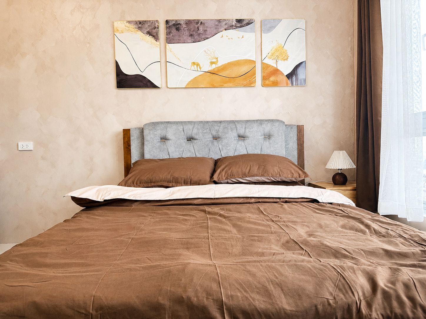 Ein Hotelzimmer mit einem Bett, einem Nachttisch, einer Lampe und drei Wandbildern.