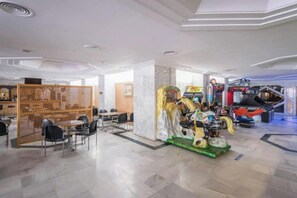 Eine Hotelhalle mit Spielbereich, Sitzgelegenheiten und einem großen Fenster.