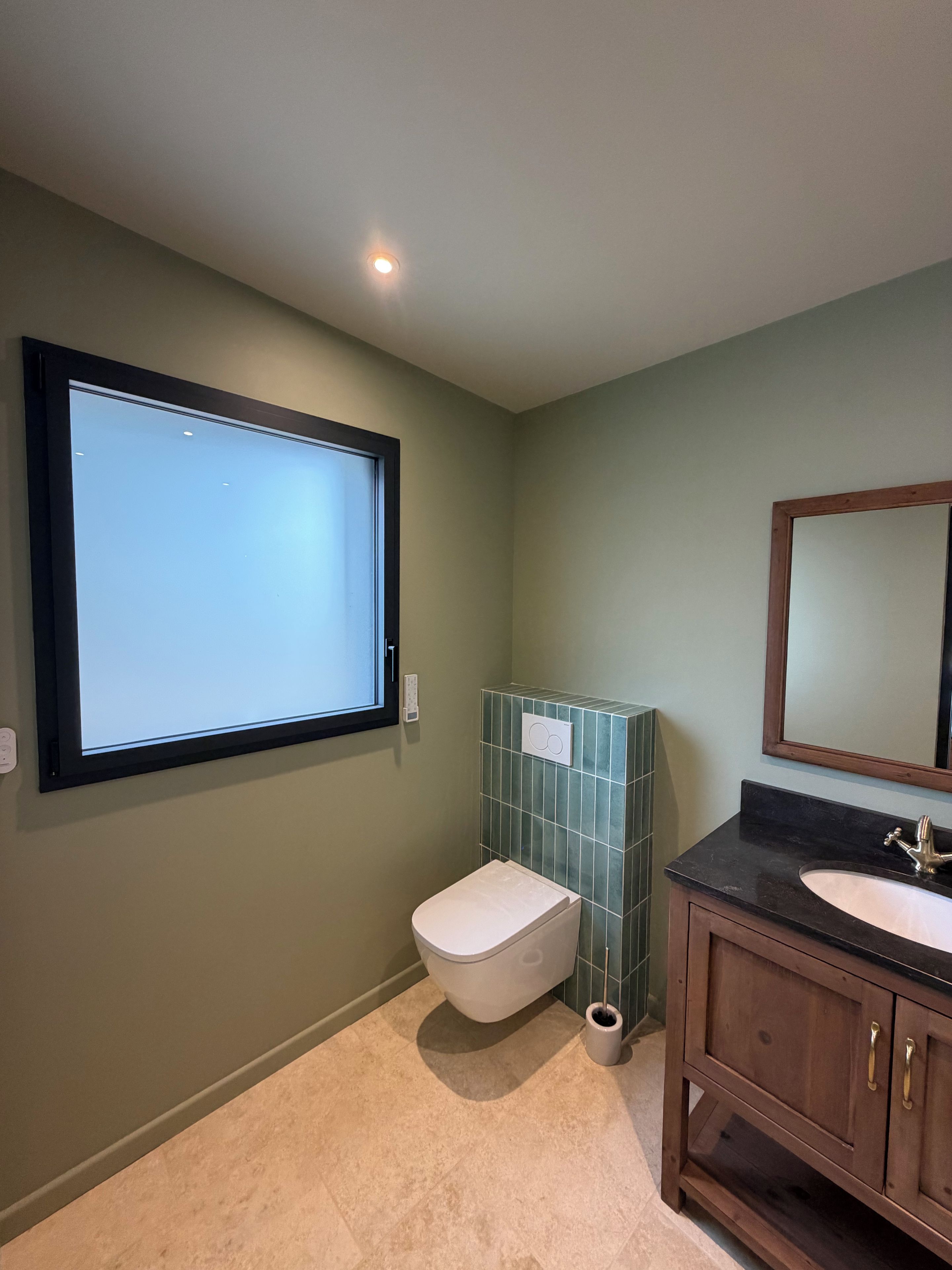 Een badkamer met toilet, wastafel en een raam.