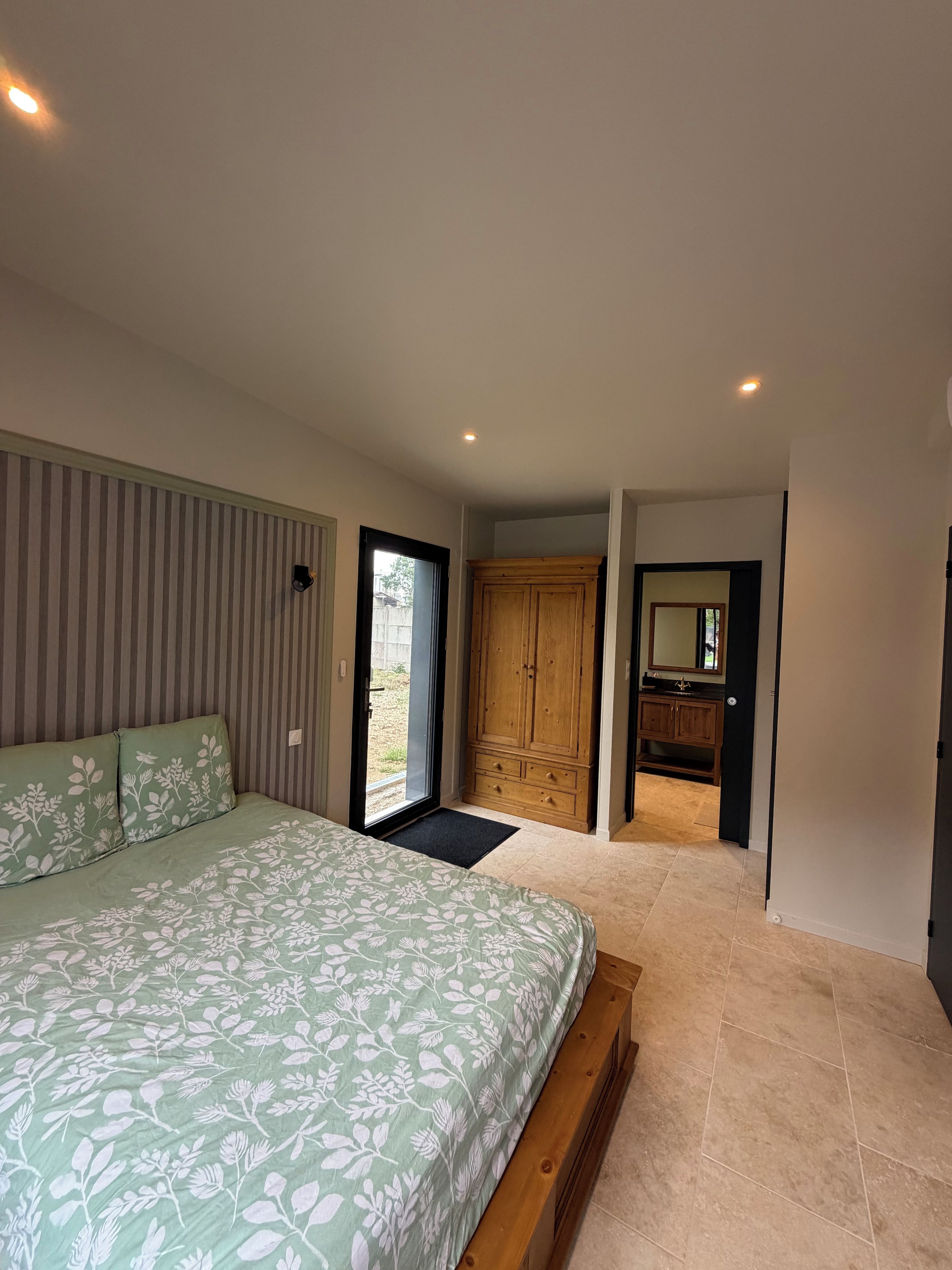 Un dormitorio con cama, armario y baño con espejo.