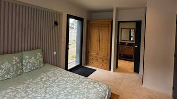 Un dormitorio con cama, armario y baño con espejo.