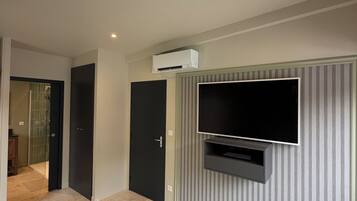 Une chambre à coucher avec un lit, un téléviseur fixé au mur et un appareil de climatisation.