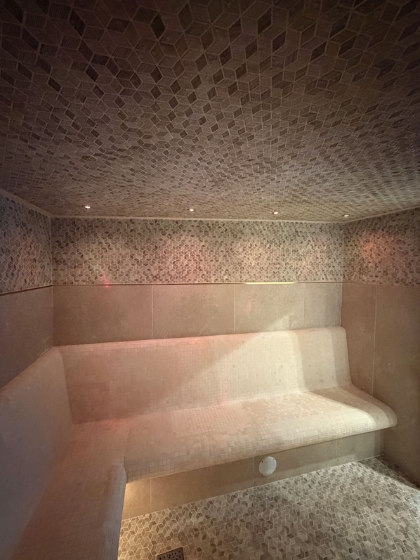 A spa room with a hexagonal patterned ceiling and walls, a seating area, and a floor with a similar pattern.