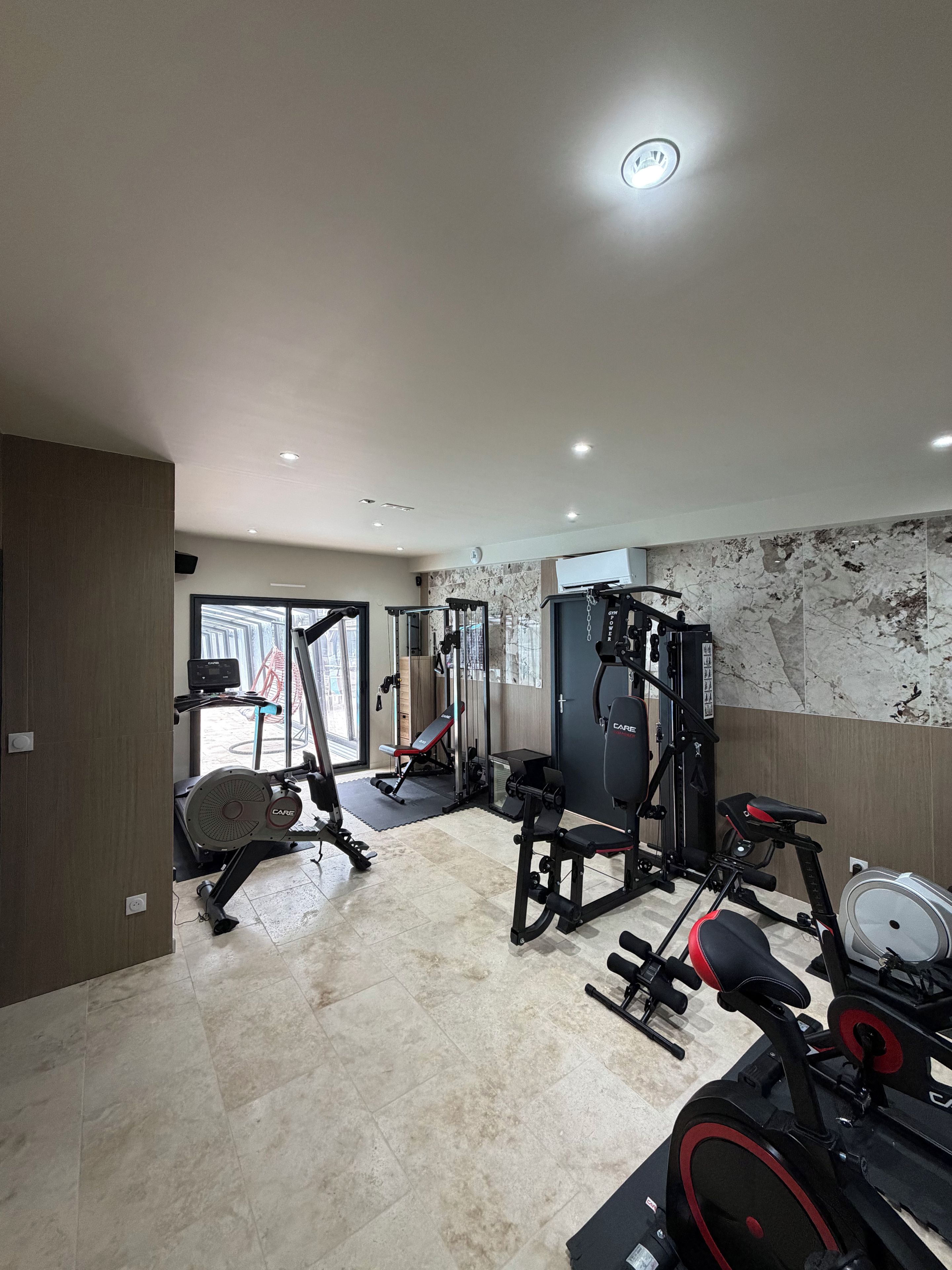 A gym with exercise equipment, a bench, and a wall with a marble-like pattern.