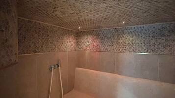 Une salle de bain avec un plafond orné d’un motif hexagonal, une baignoire et un espace douche.