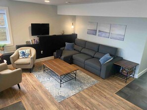 A living room with a sofa, armchair, coffee table, and a television.