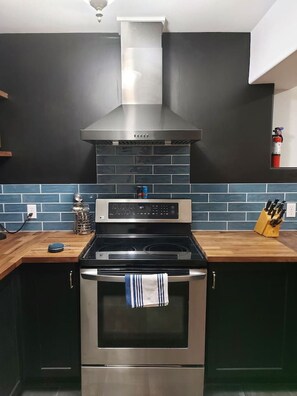 A kitchen with a stainless steel range hood, a built-in oven, and a tiled backsplash.