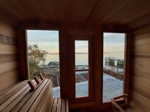 A wooden cabin with a bench and a view of a body of water through large windows.