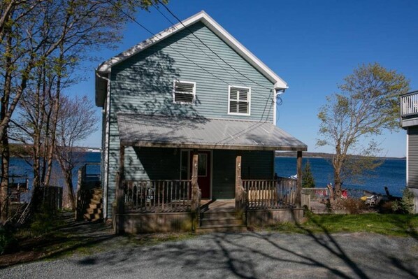 A two-story house with a front porch, a garage, and a view of the water.