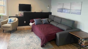 Una sala de estar moderna con sofá, sillón y televisor de pantalla plana.