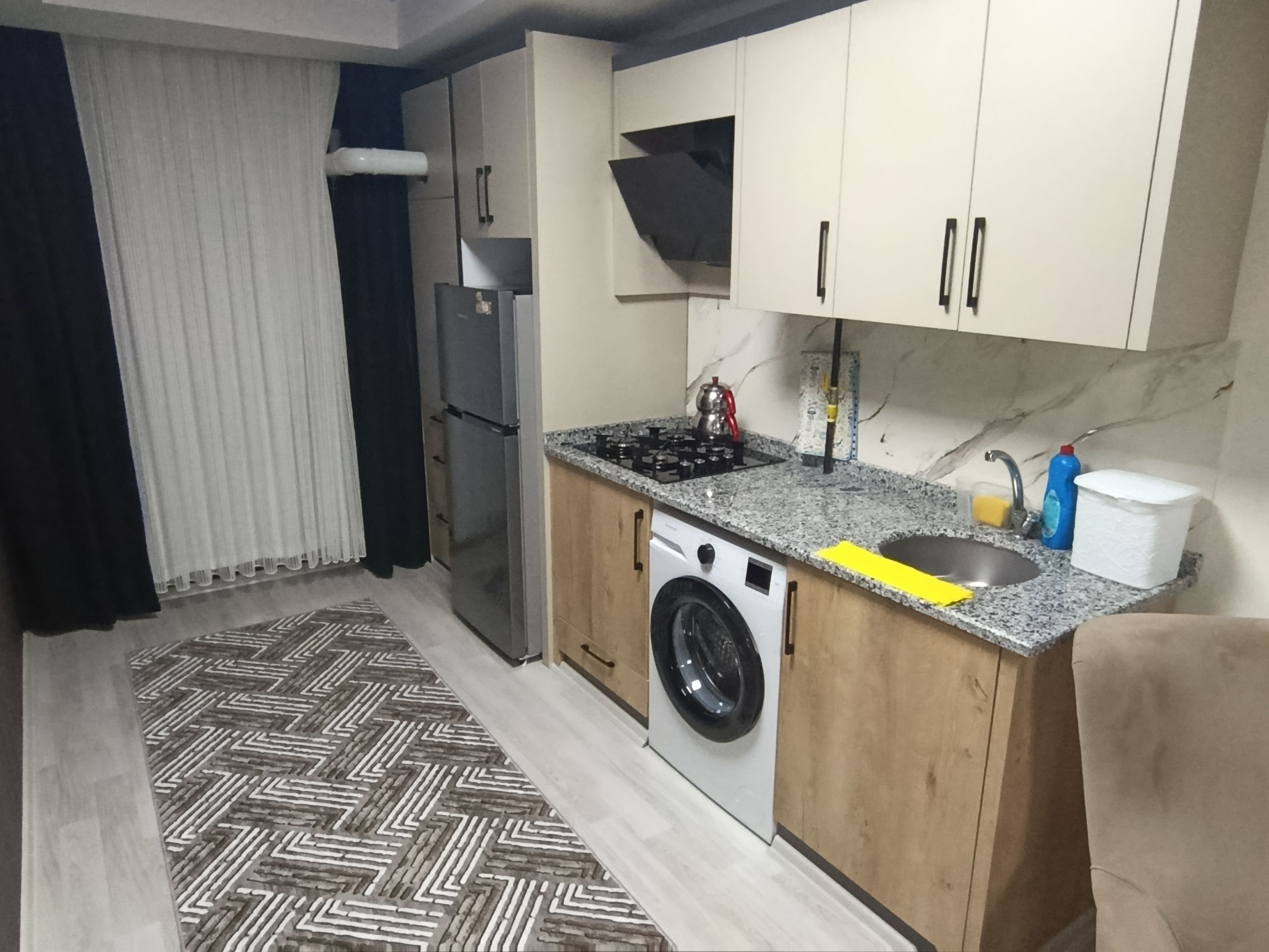 Una cocina compacta con lavadora, refrigerador, estufa y lavaplatos.