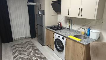 Una cocina compacta con lavadora, refrigerador, estufa y lavaplatos.