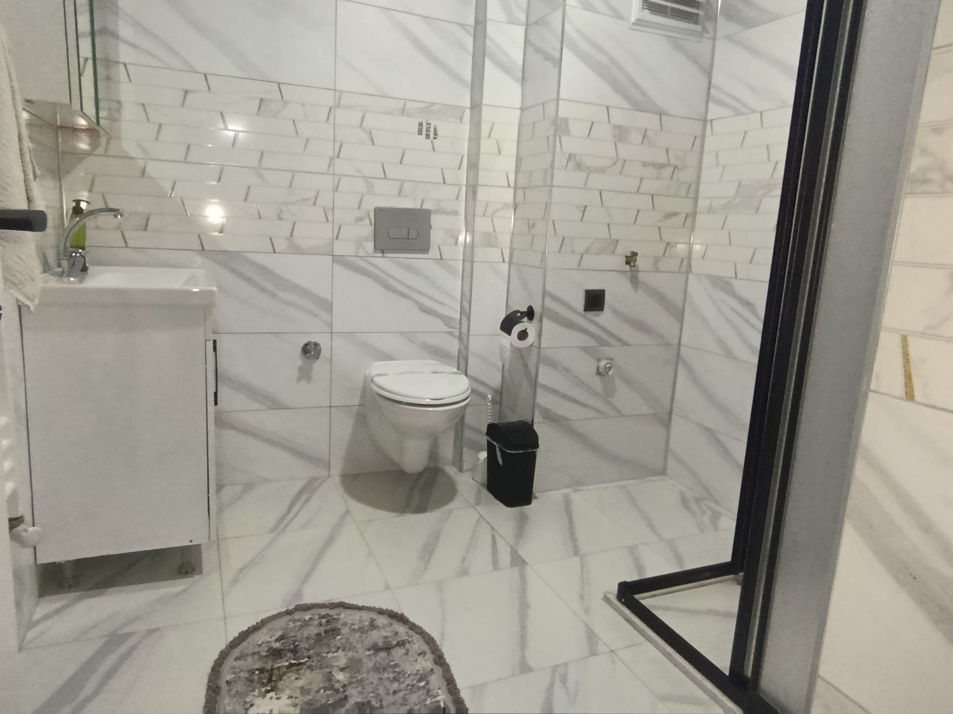 Un baño con inodoro, bidé y cabina de ducha de vidrio.
