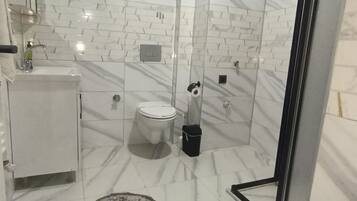 Un baño con inodoro, bidé y cabina de ducha de vidrio.