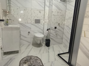 Un baño con inodoro, bidé y cabina de ducha de vidrio.