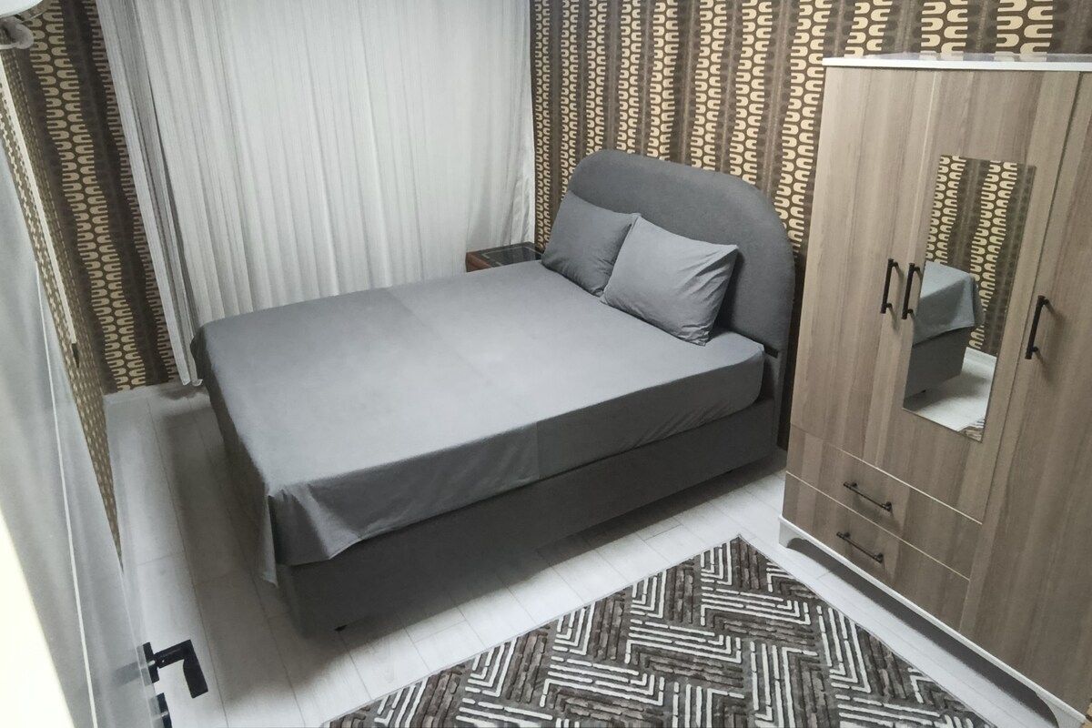 Un dormitorio con cama, armario y una alfombra estampada.