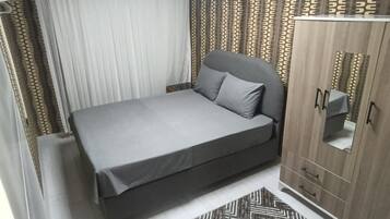 Un dormitorio con cama, armario y una alfombra estampada.