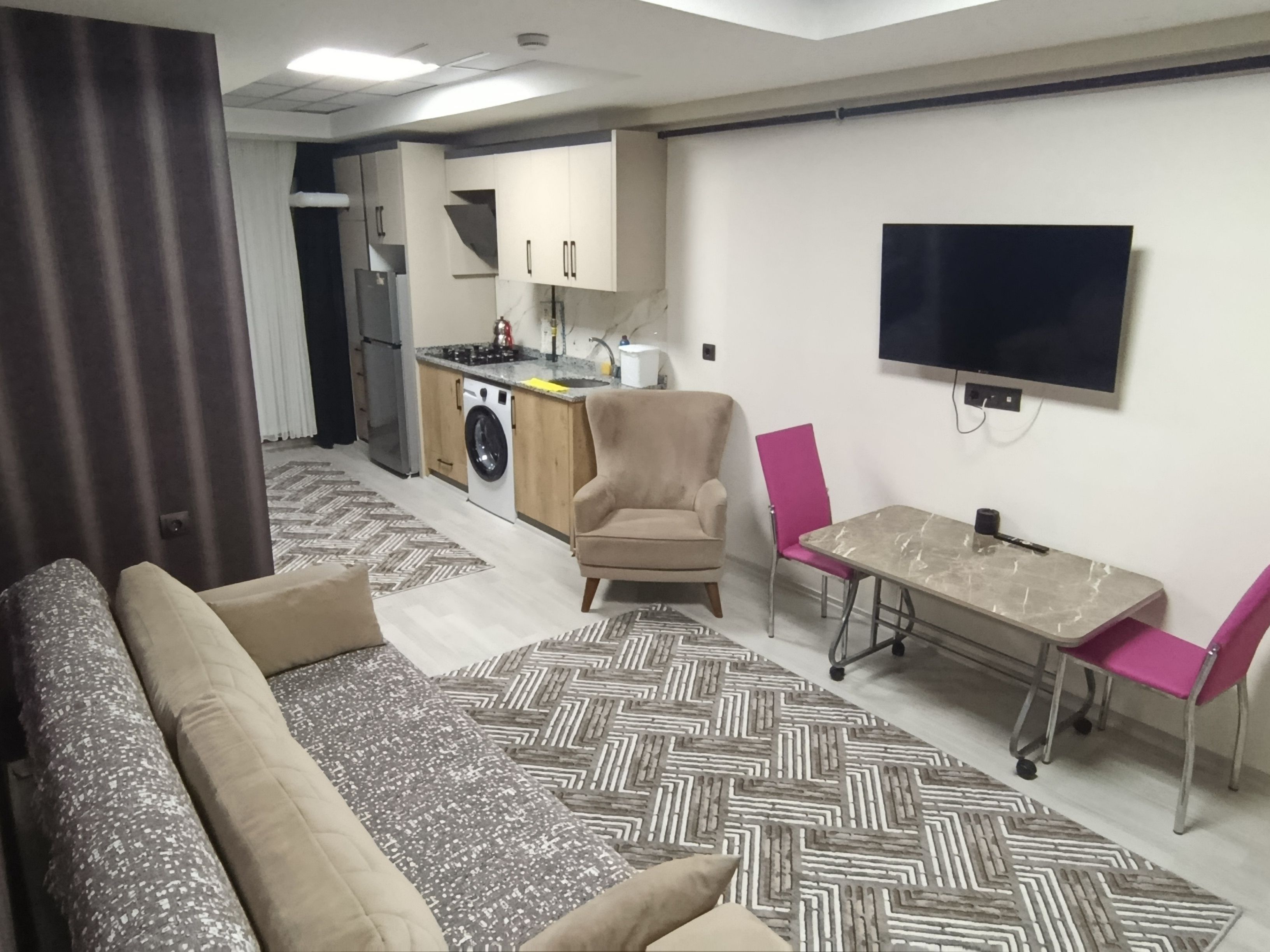 Sala de estar moderna com sofá, mesa de jantar e área de cozinha ao fundo.