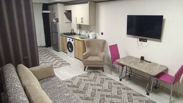 Sala de estar moderna com sofá, mesa de jantar e área de cozinha ao fundo.