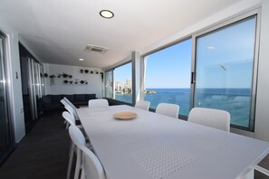 A modern dining area with a large table, white chairs, and a view of the sea. - TOR Serena 15C in Benidorm (Benidorm)