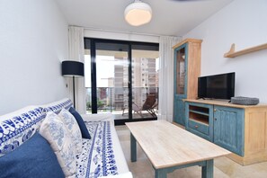 A modern living room with a sofa, a coffee table, a TV, and a balcony with a view of buildings. - Torre Ipanema 6A in Benidorm (Benidorm)
