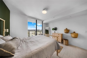 A modern bedroom with a large bed, a dresser, a mirror, and a view of the city. - Brickell Skyline With Rooftop Pool Spa (Miami)