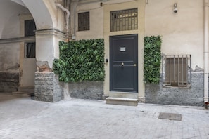 A building facade with a dark door, a window with bars, and a small window with a metal grille. - Room 'Soleil Rooms - Salvia' (Catania)