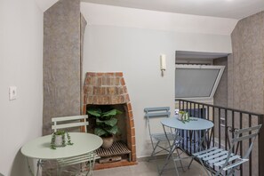 Una habitació amb una llar de pedra, una taula petita amb cadires i un balcó amb barana.