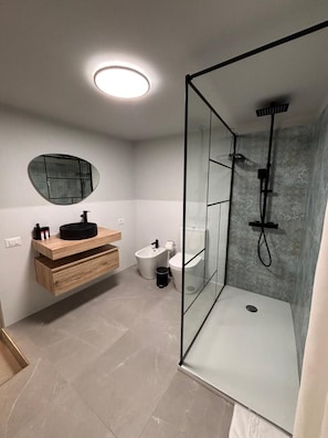 Ein modernes Badezimmer mit einer Duschkabine aus Glas, einem runden Spiegel und einem Holzbadezimmer.