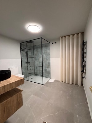 Ein modernes Badezimmer mit Glasdusche, Holztresen und Toilette.