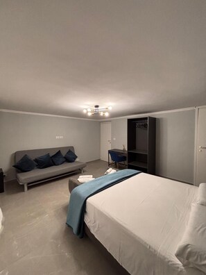 Ein Schlafzimmer mit einem Bett, einer Couch, einem Schreibtisch und einem Kleiderschrank.