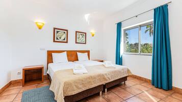 Una habitación de hotel con cama, mesita de noche, ventana con cortinas e iluminación en la pared.
