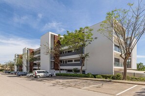 A modern multi-story building with a parking lot in front. - Marina Village Pool Garage Near Meia Praia (Lagos)