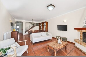 Ein geräumiger Wohnbereich mit einem weißen Sofa, einem Holztisch und einem Kamin.