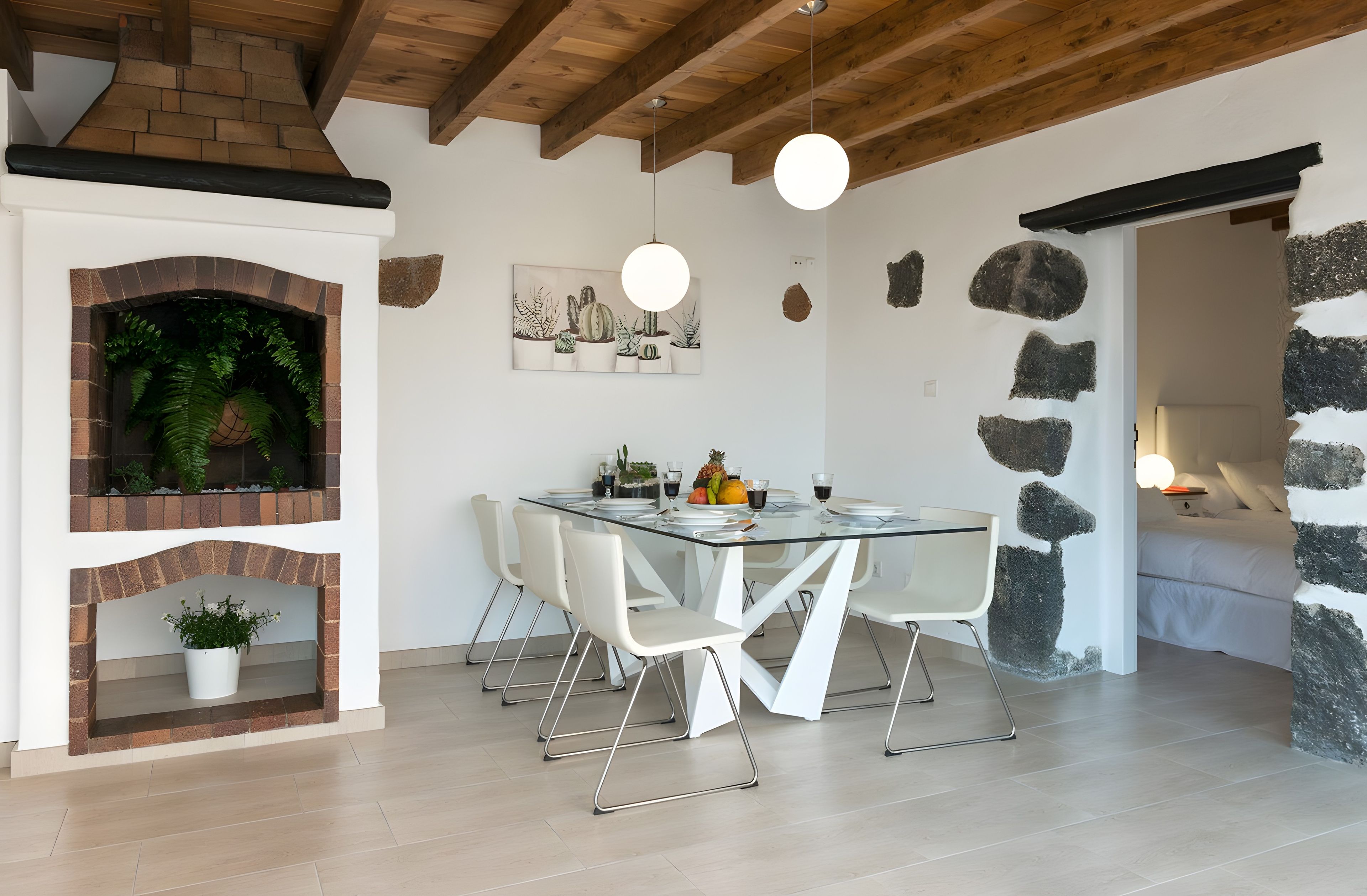 Una cucina moderna con forno in mattoni integrato, sedie bianche e un tavolo da pranzo in vetro.