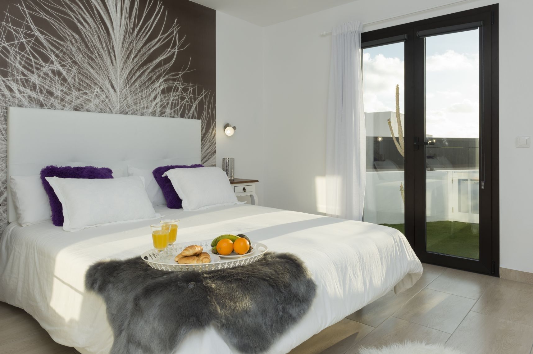 Un dormitorio moderno con una cama grande, una bandeja de desayuno y vistas al exterior.
