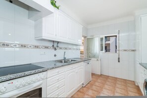 A kitchen with white cabinets, a granite countertop, a built-in oven, and a washing machine. - Casa da Gal Meia Praia Balcony AC (Lagos)