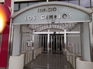 Ein verschlossenes Eingangstor mit einem Schild, auf dem 'EDIFICIO LOS GEMEOS' steht, und einem Verbotsschild für parkende Fahrzeuge.