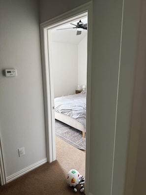 A bedroom with a bed, a ceiling fan, and a wall-mounted thermostat. - Perfect 3-bedroom house with AC in enchanting McKinney (McKinney)