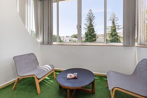 A room with two chairs and a small table, a window with curtains, and a view of trees and buildings. - Chilling in Lagos 5BR Villa With Private Pool (Lagos)