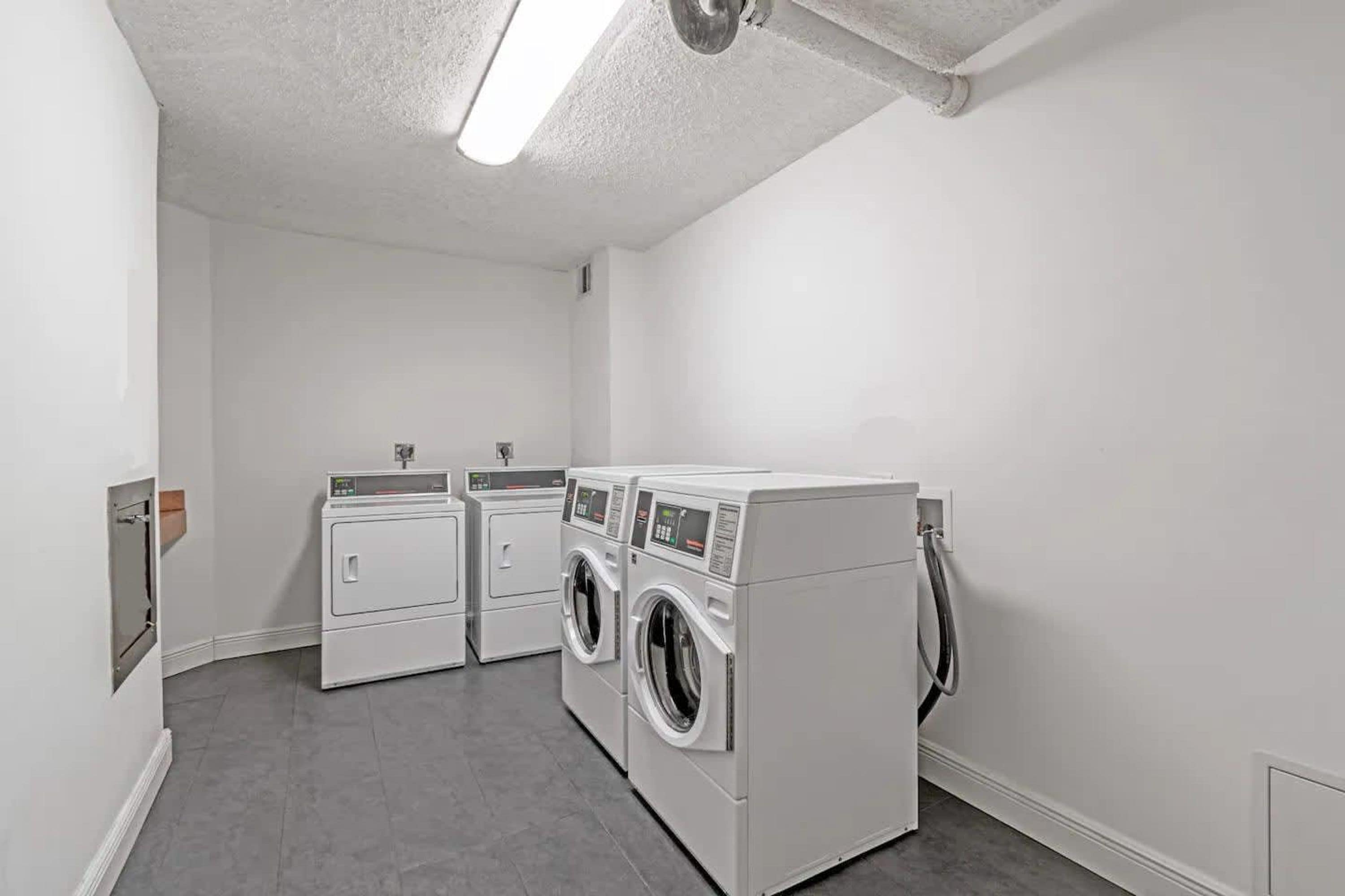 A laundry room with two dryers and two washing machines.