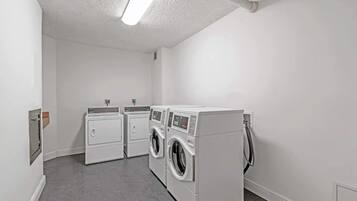 A laundry room with two dryers and two washing machines.