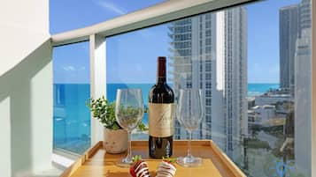 Un balcon avec une bouteille de vin, deux verres et des fraises disposées sur un plateau.