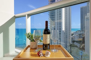 Un balcon avec une bouteille de vin, deux verres et des fraises disposées sur un plateau.