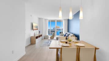 A modern dining area with a view of the city skyline, a large window, and a blue accent wall.