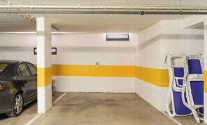 Un parking avec une voiture garée dans un espace prévu à cet effet, une rampe d’accès pour fauteuils roulants et un mur avec une bande jaune.